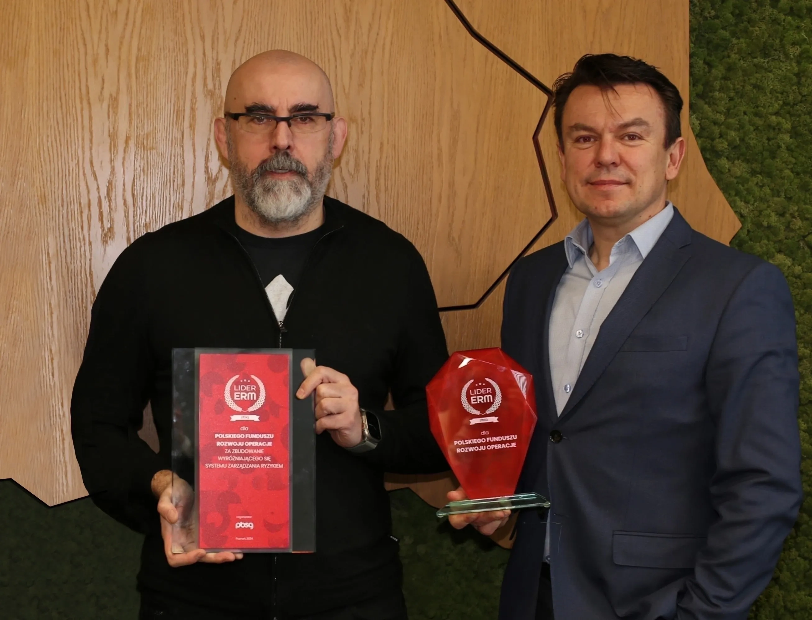 Dwóch mężczyzn stojących przy ścianie ze statuetkami